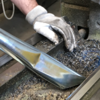 Operator uses a Depureco TB industrial vacuum to collect metal chips, swarf, and machining debris from a machine tool.