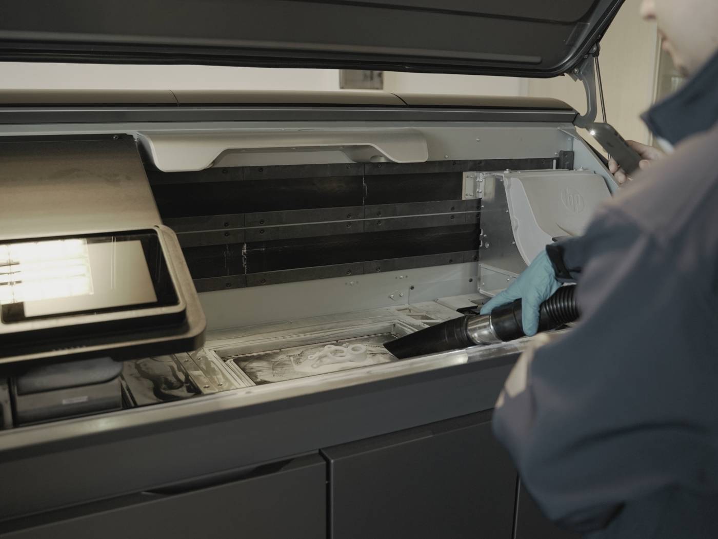 Technician vacuuming powder bed of 3D printer with Depureco industrial vacuum