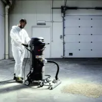 Depureco MINIBULL industrial vacuum with a wide floor tool collecting granular material from a concrete floor.