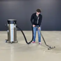 Operator uses a stainless steel Depureco WD 132 industrial vacuum and floor squeegee to recover liquid from a concrete floor.