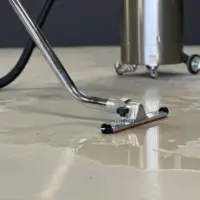 Close-up of a wet-pickup floor squeegee connected to the WD 132 vacuum collecting liquid from an industrial floor.