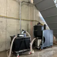 Mobile tiltable pre-separator connected to a Depureco PUMA industrial vacuum beneath a bulk material storage hopper.
