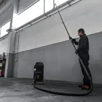 Operator uses the M PRO industrial vacuum with a long-reach cleaning tool to remove dust from overhead building surfaces.