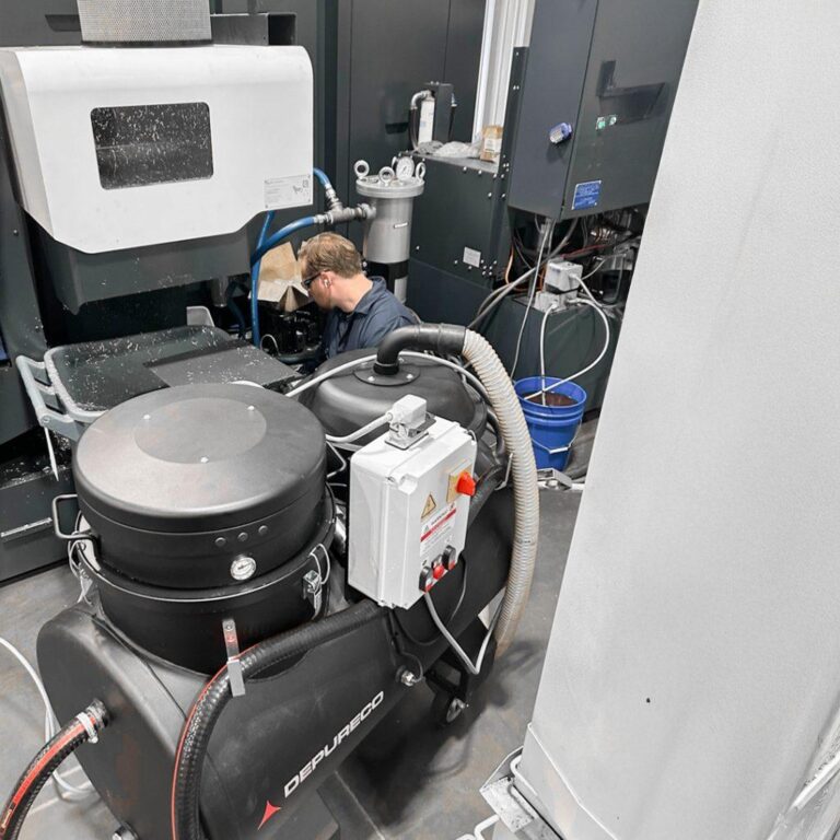 Depureco industrial vacuum beside a CNC machine for metal chip and swarf recovery